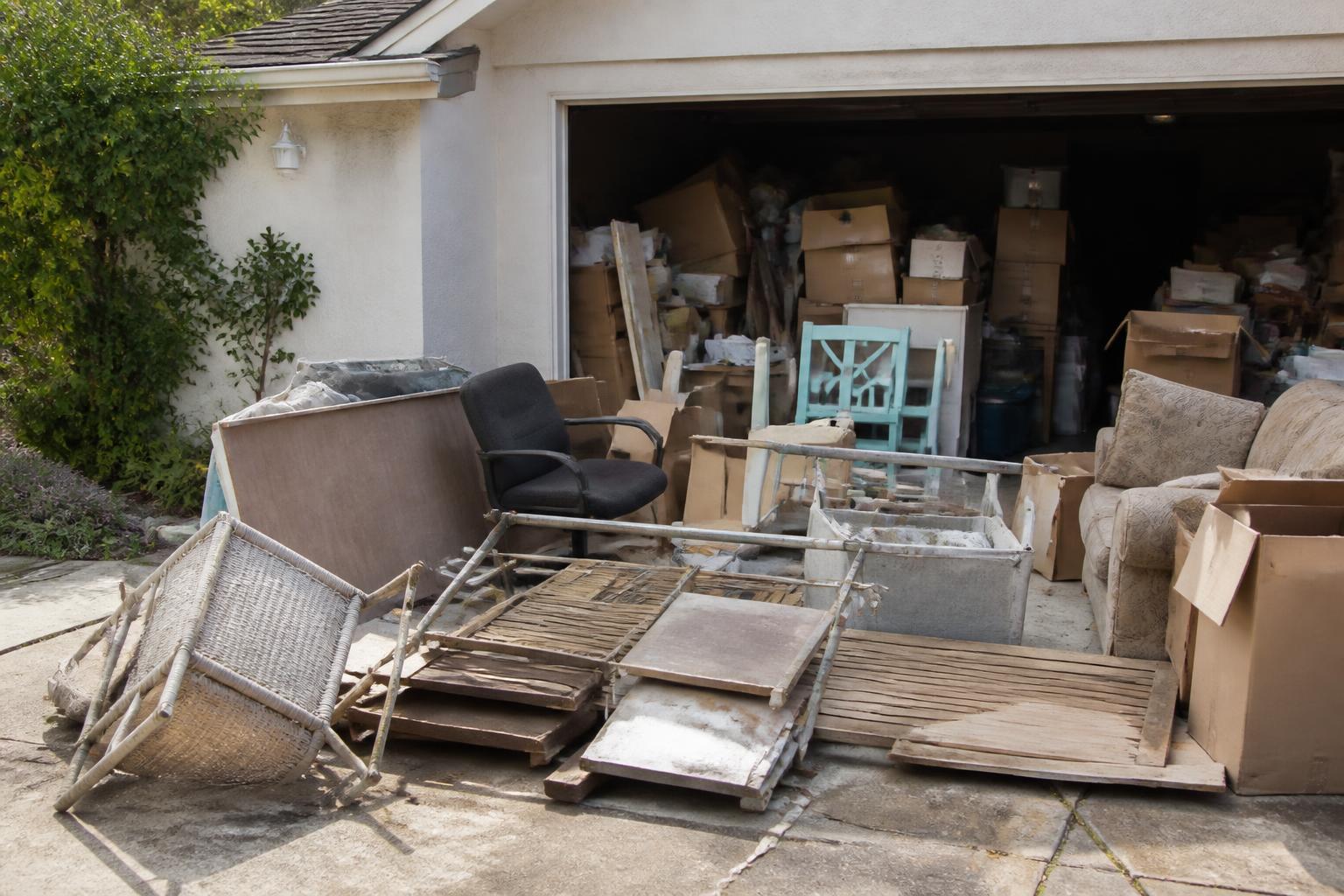 Old furniture and clutter staged outside a residential garage for removal
